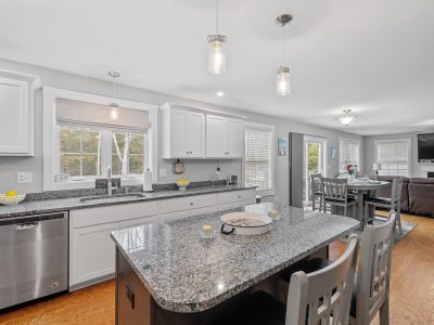 A kitchen with white cabinets, a gray granite countertop, and modern appliances.
